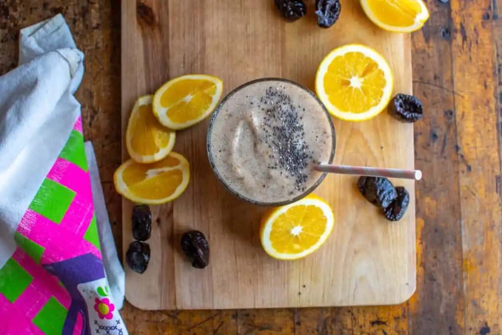 Banana Prune Smoothie from Hola Jalapeno on a wooden tray with prunes and lemons