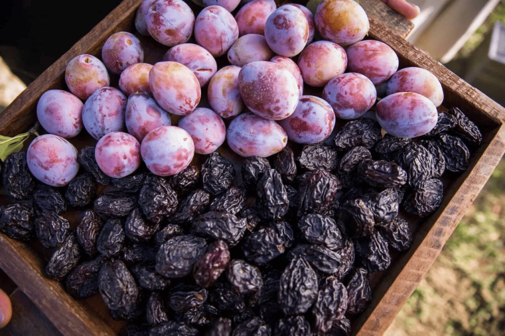 a wooden tray filled with both plums and prunes