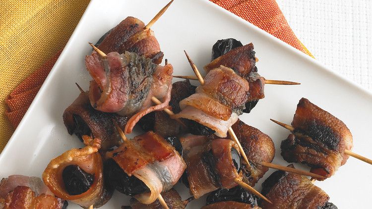 a white plate with Martha Stewart's Bacon Wrapped Prunes secured with toothpicks