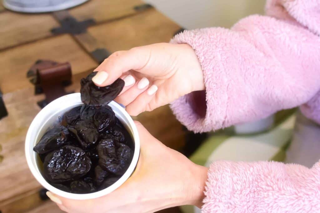 hand grabbing prunes from a bowl
