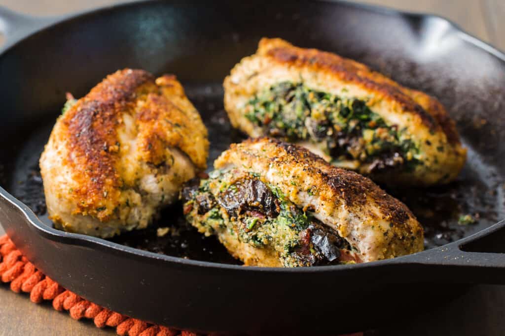 a cast iron pan filled with stuffed chicken breasts