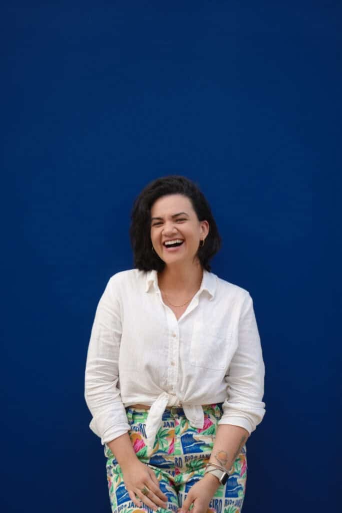 woman wearing white shirt standing on a blue wall