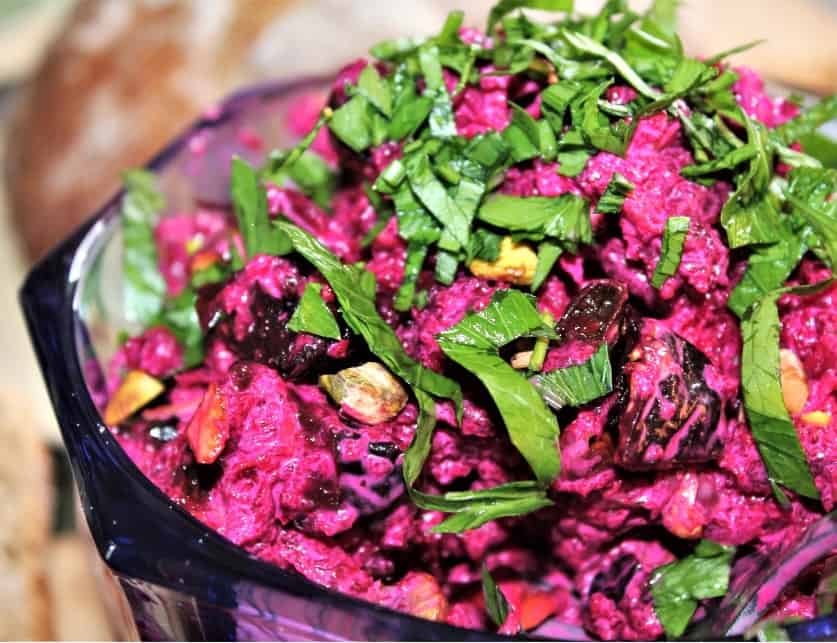 a bowl of beet salad with prunes and pistachios
