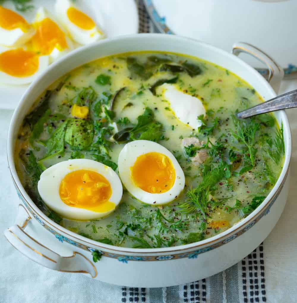 a bowl of green borscht topped with an egg