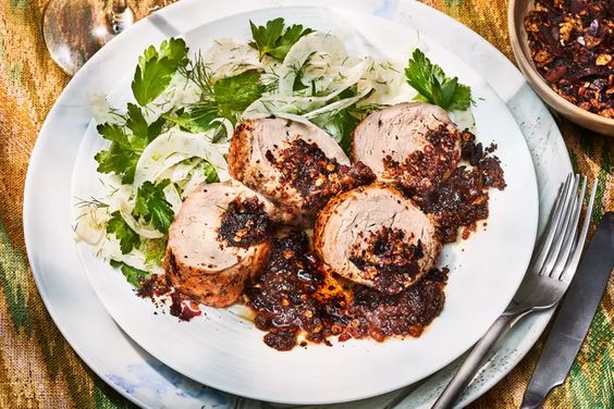Roasted pork tenderloin with warm plum vinagrette on a plate with fennel salad