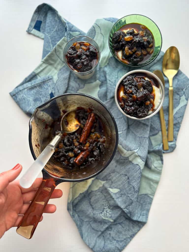 a spoon of rum stewed prunes and two bowls filled with the mixture