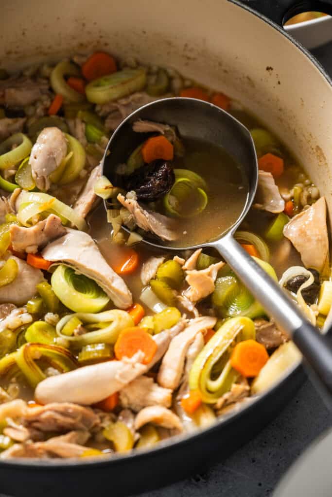 a serving spoon in a pot of Cock-a-leekie, a scottish chicken and leek stew. 