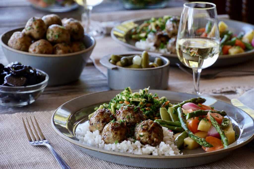 a plate of Chicken Marbella Meatballs from Weekend at the Cottage on top of rice, served with veggies
