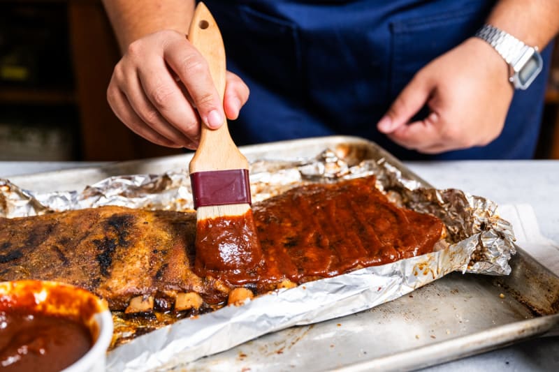 adding a homemade BBQ sauce to ribs