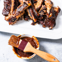 bbq sauce recipe - bbq sauce on brush with rubs in background