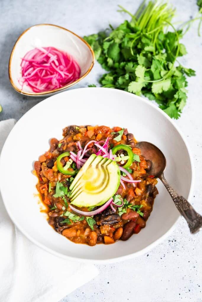 Accidentally Vegan Vegetarian Chili featuring California Prunes | Opt-in content Accidentally Vegan Vegetarian Chili featuring California Prunes garnished with sliced avocado and pickled onions