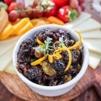 prune olive relish in a white bowl garnished with orange zest and fresh rosemary