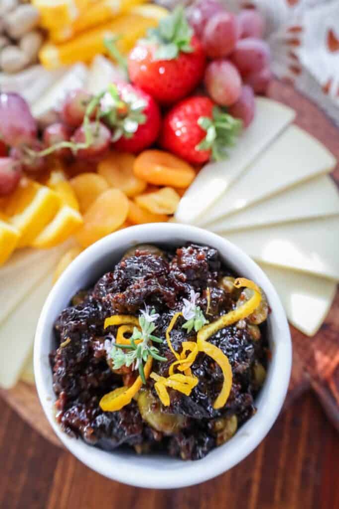 prune olive relish in a white bowl on a cheeseboard