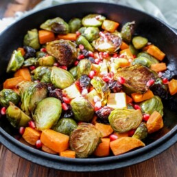 roasted brussels sprouts with sweet potatoes and garnished with pomegranate arils