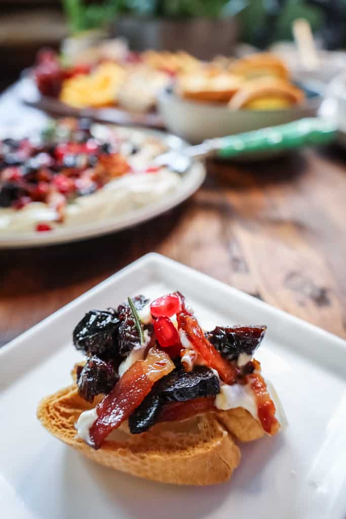 whipped ricotta on a crostini with prunes, bacon and pomegranate