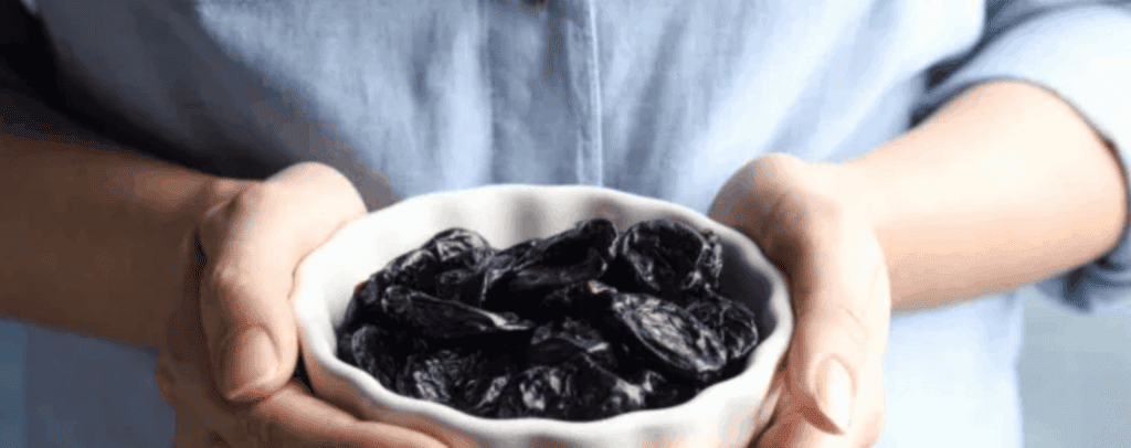 Prunes may contribute to healthier bones. Image: women holding prunes in a bowl