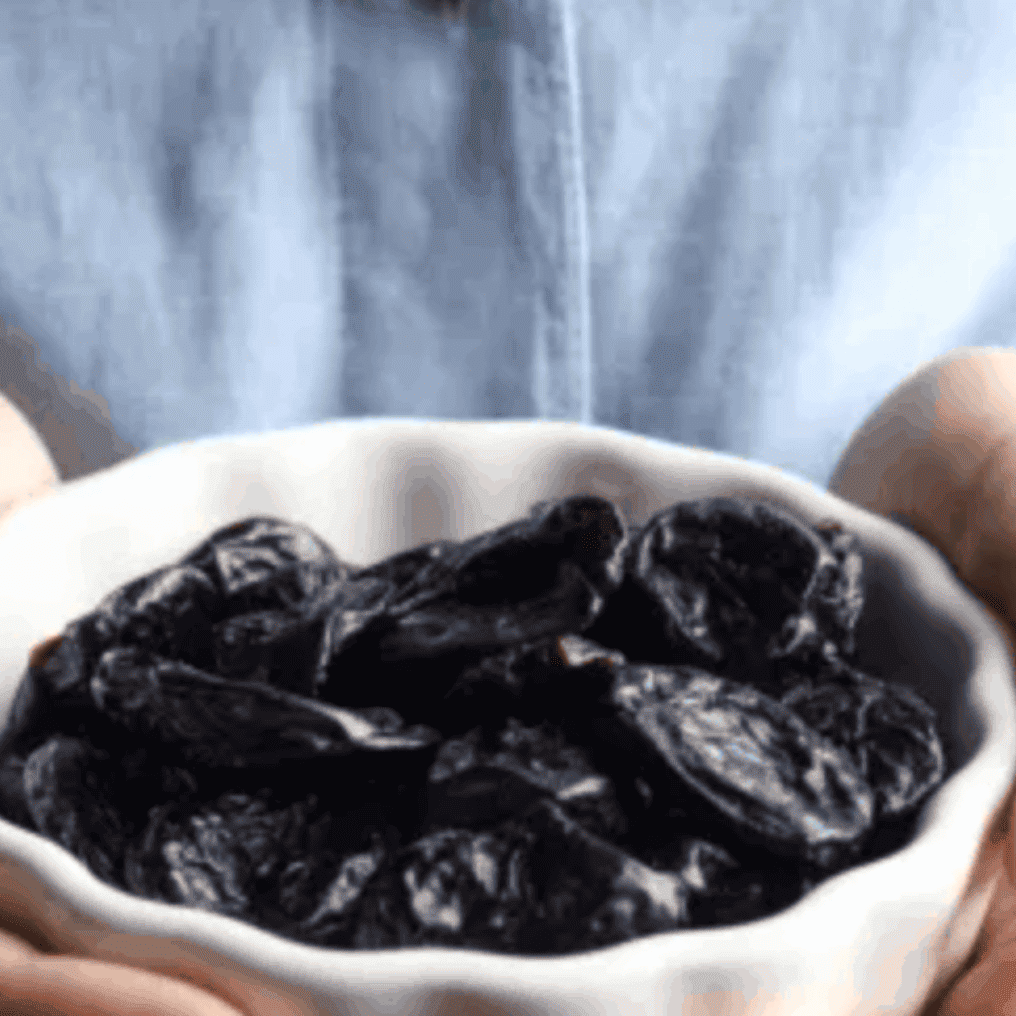 Prunes may contribute to healthier bones. Image: women holding prunes in a bowl