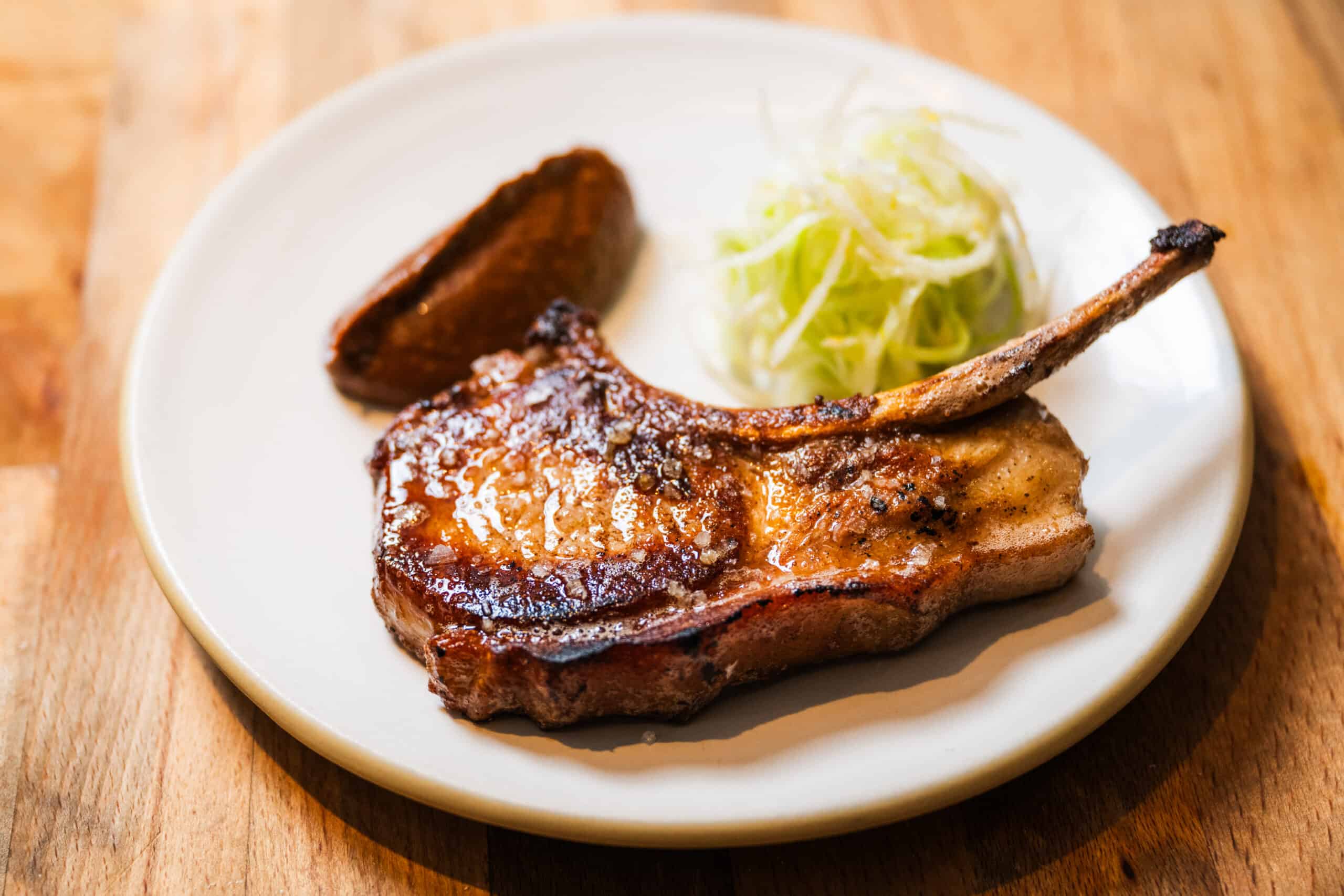 Ana Castro's pork chop on a plate garnished with slaw and prune mole
