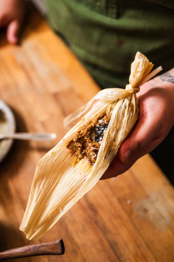 woman holding sweet corn tamale with prunes and pecans
