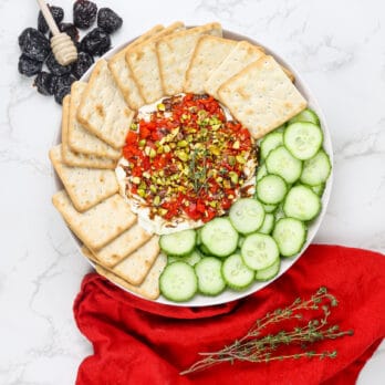 whipped feta dip on a plate surrounded by crackers and cucumbers