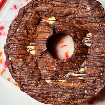Overhead view of chocolate bundt cake topped with toasted walnuts and drizzled with chocolate