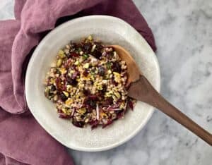 Bowl of Prune and Farro Salad Recipe with Zesty Herb Vinaigrette with wooden spoon