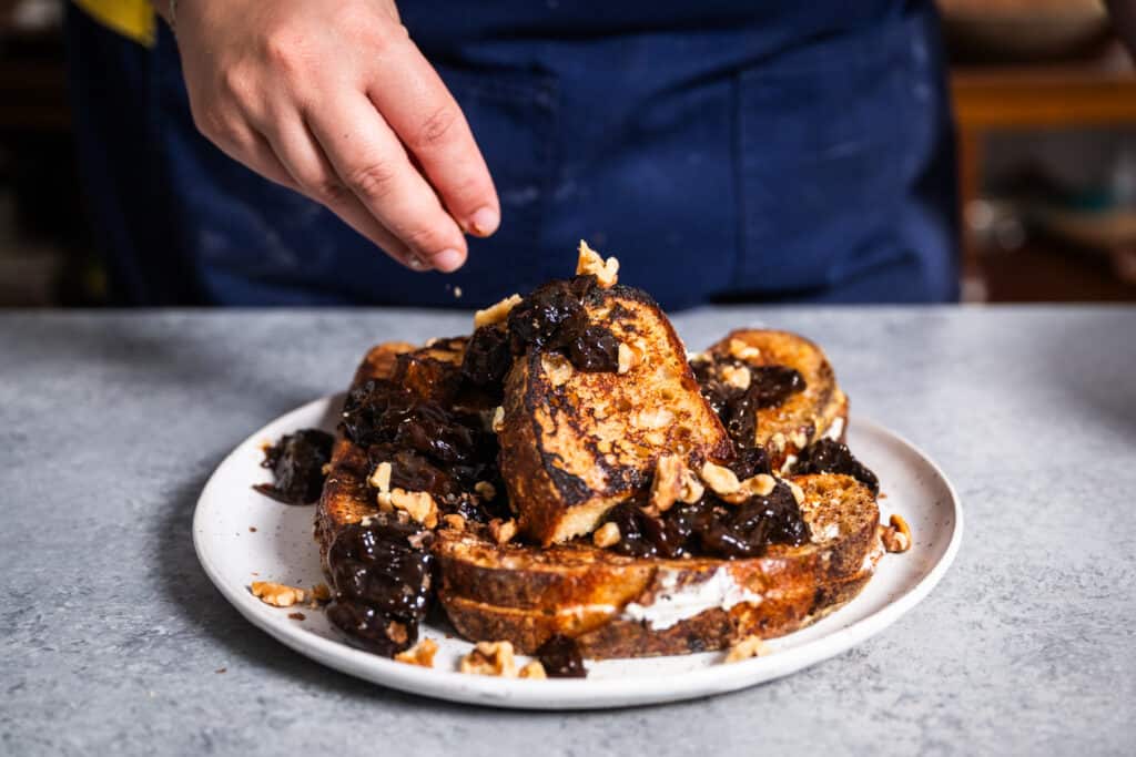 topping Tracy Malechek-Ezekiel's stuffed french toast with chopped walnuts and prune compote
