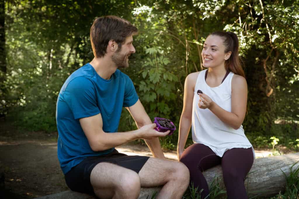 Couple sitting and eating prunes after a work out