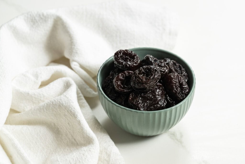 prunes in a blue bowl on a white table