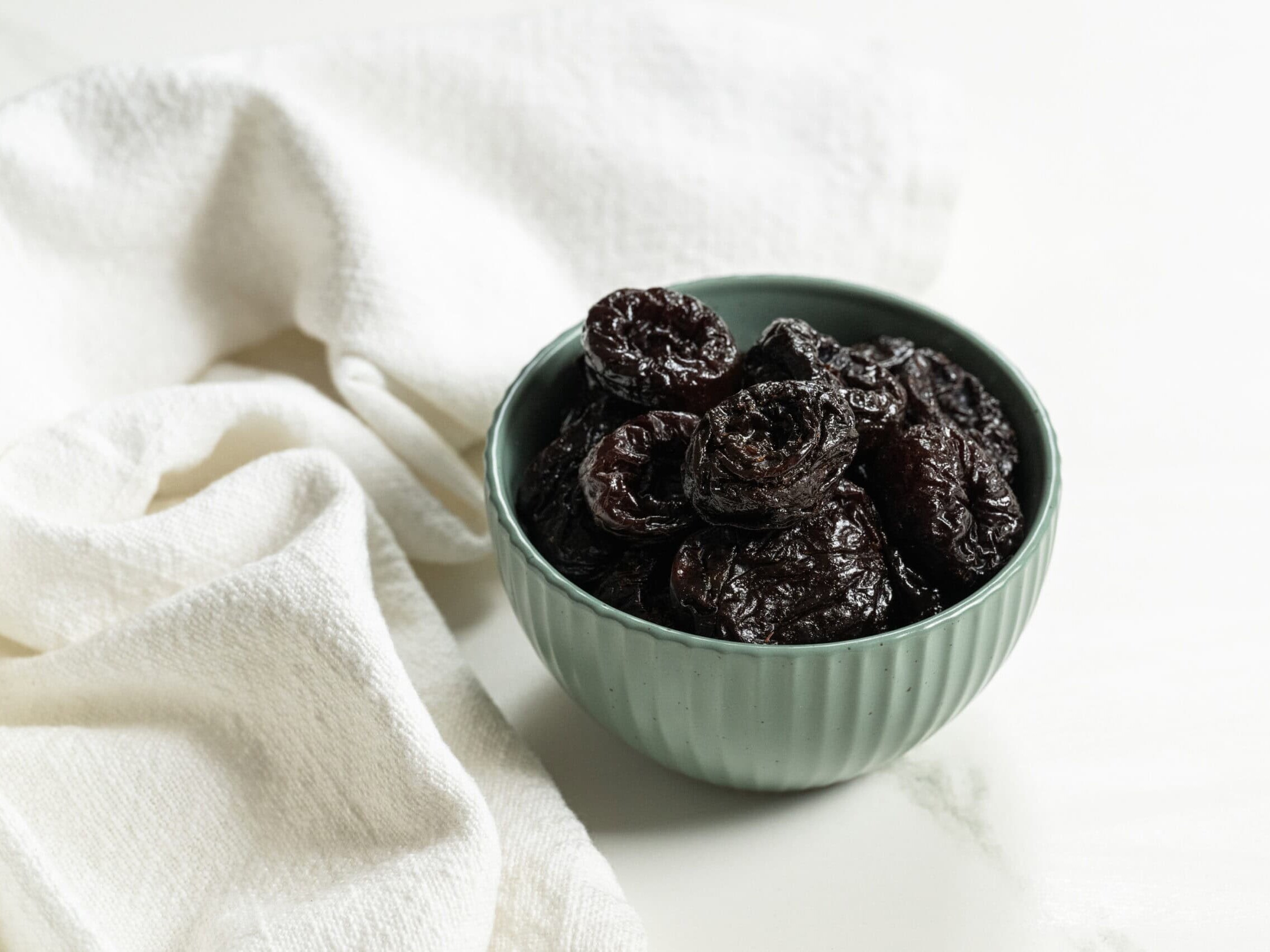 prunes in a blue bowl on a white table