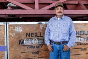 Jose Raya standing next to a crate bearing his name