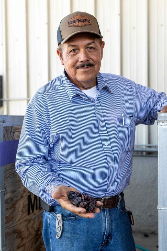 Prune grower Jose Raya proudly holding his prunes in his hand