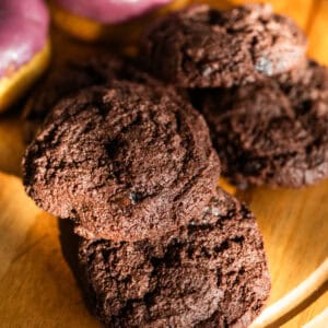 chocolate cookies and purple doughnuts on a wooden tray