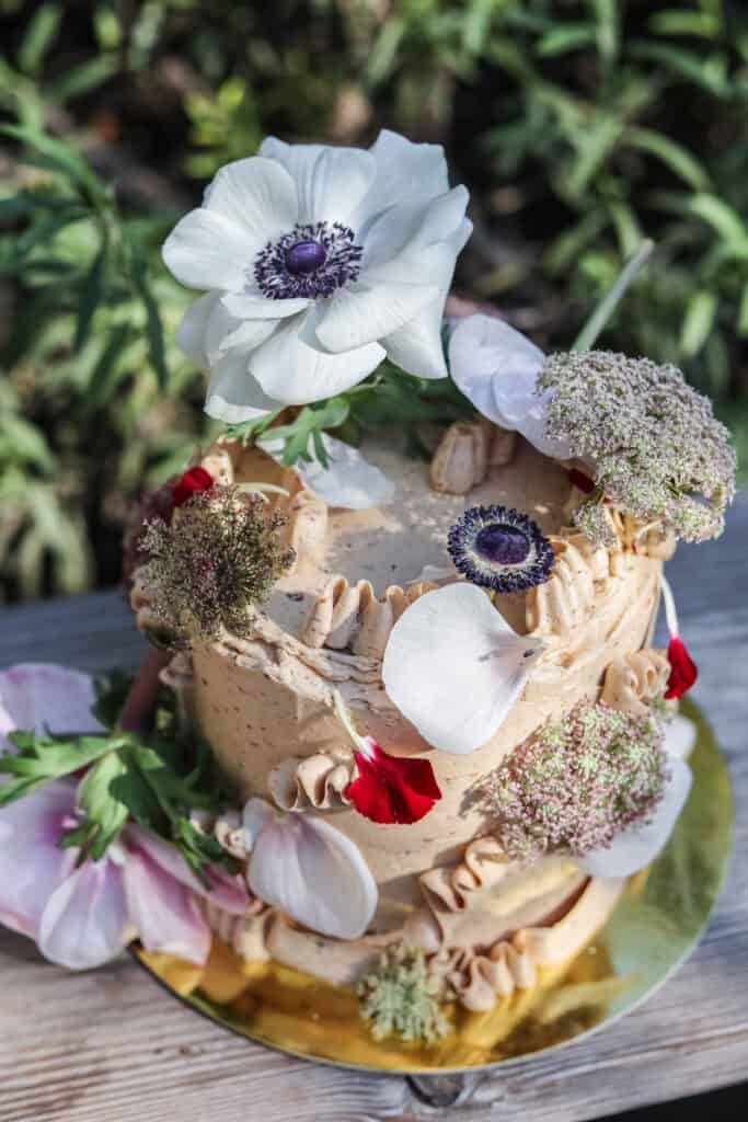 prune coconut cake frosted with swiss buttercream and topped with fresh flowers