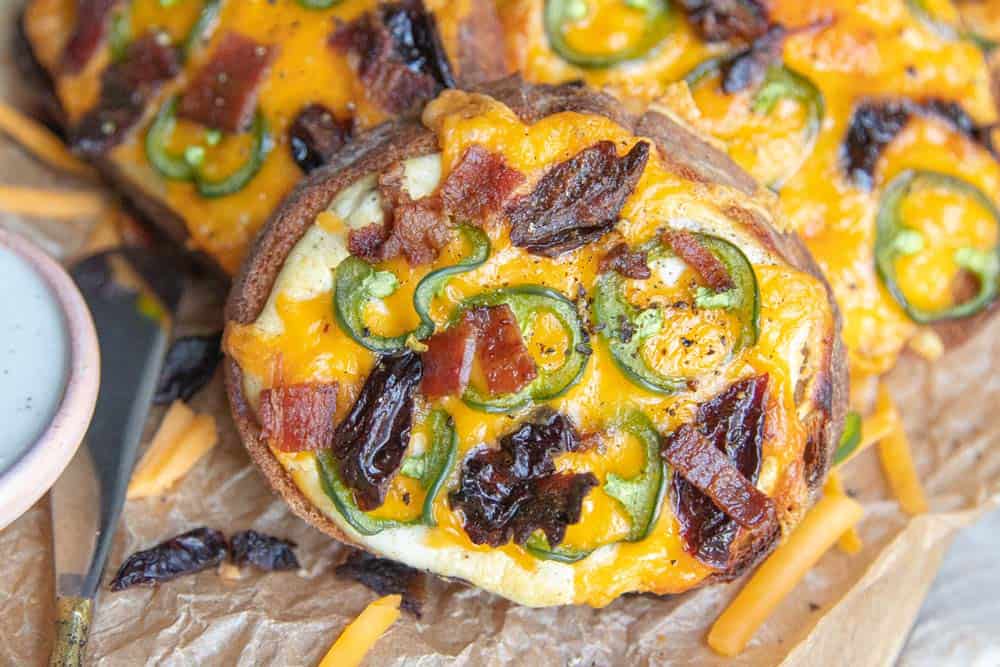 A close up of one pieces of Sweet and Spicy Cheese Toast with all the fixin's from sliced prunes and jalapenos to crispy bacon.