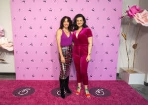 Two women standing on a pink carpet