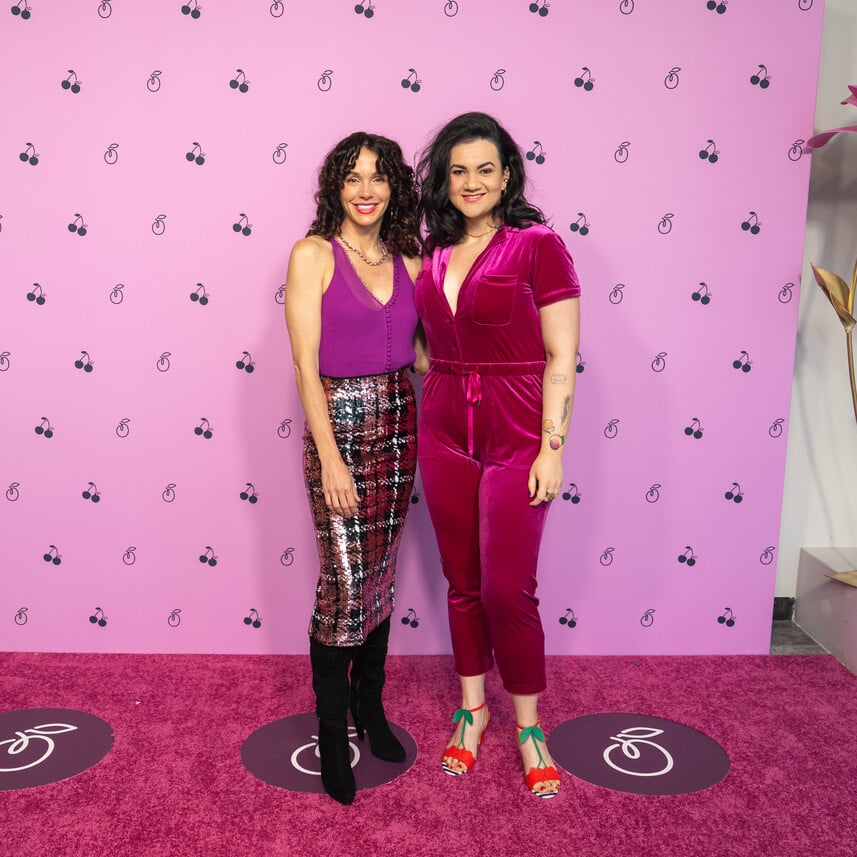 Two women standing on a pink carpet