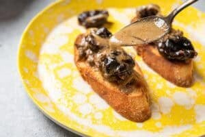 spooning sauce over chicken livers with prunes on toast