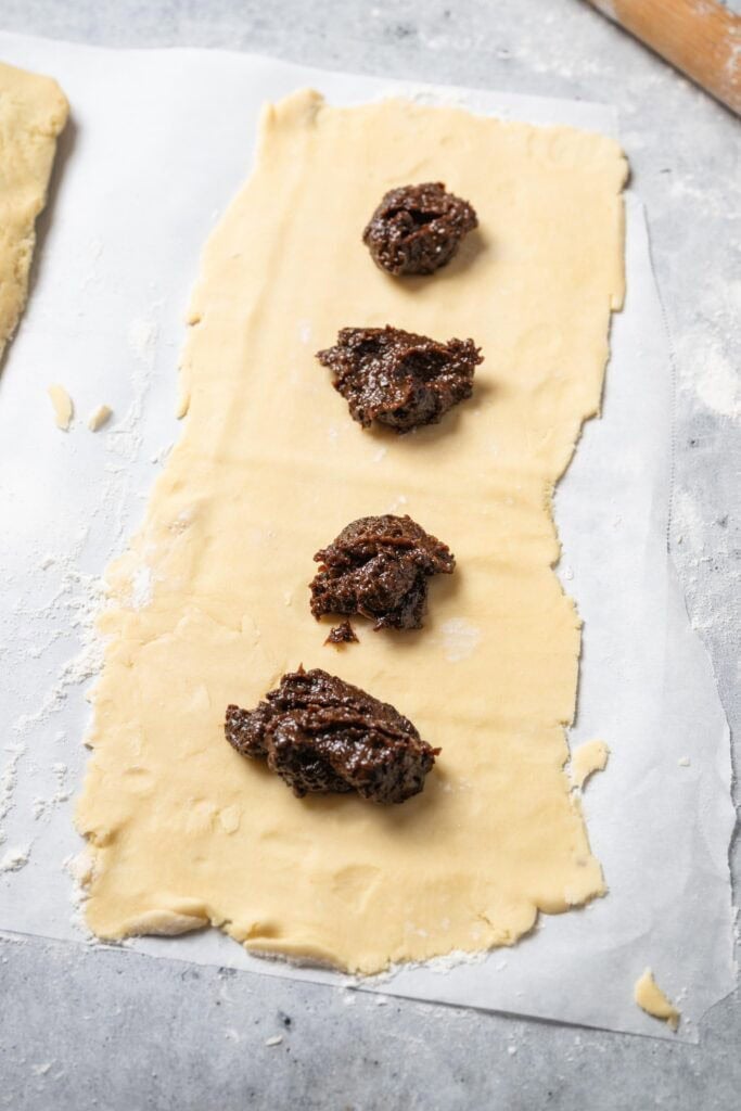 prune newton dough rolled out with dollops of prune filling