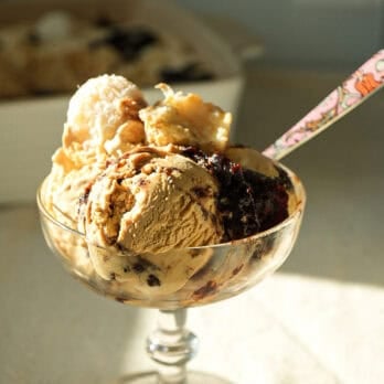 dulce de leche no churn ice cream in a dish toppedno churn ice cream topped with with Beijinho Fudge Balls in a glass ice cream dish