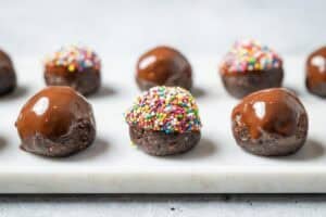 chocolate prune balls with sprinkles on a white platter