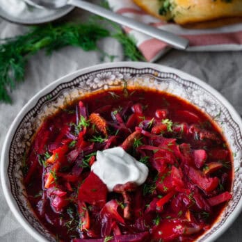 ukrainian borshch recipe from author ana voloshyna in a black and white bowl garnished with sour cream