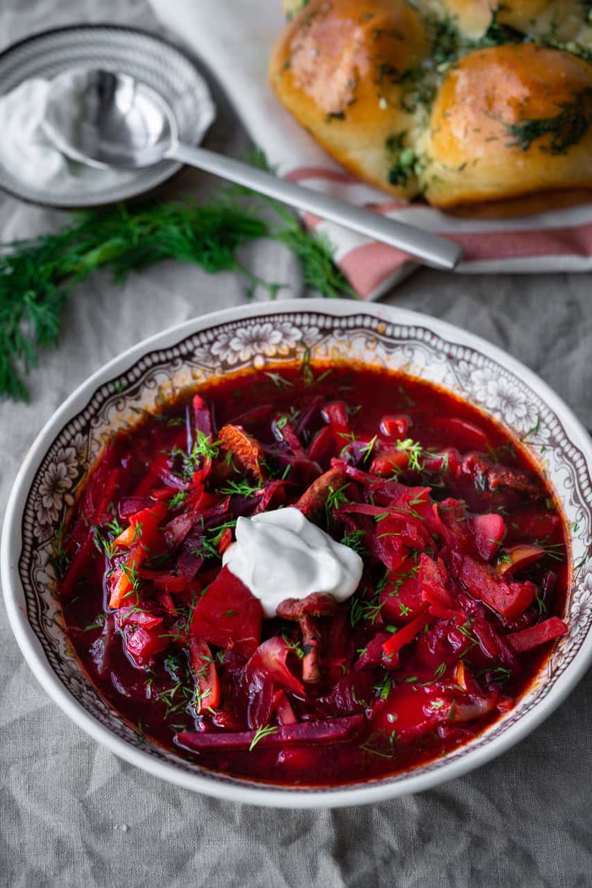 ukrainian borshch recipe from author ana voloshyna in a black and white bowl garnished with sour cream