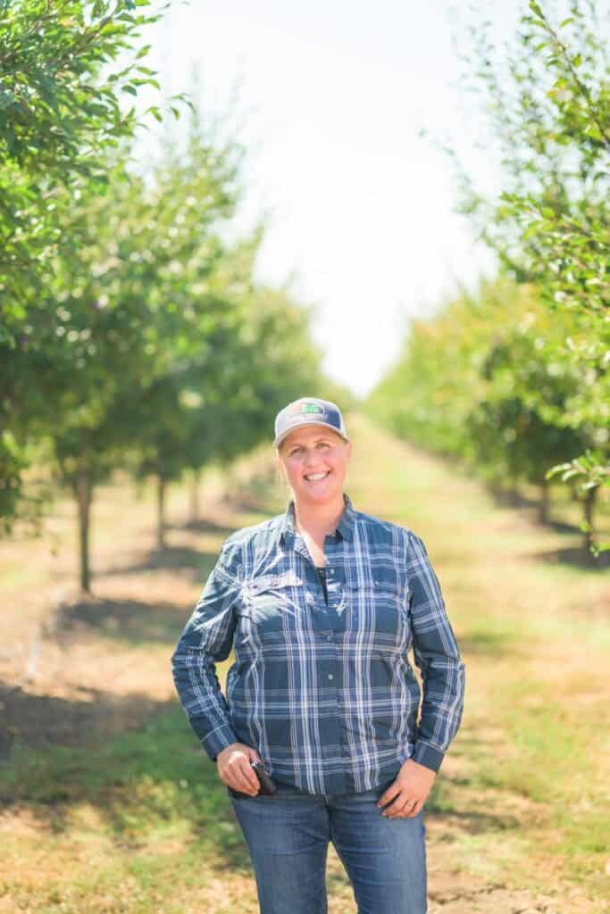 woman stands in prune orchard
