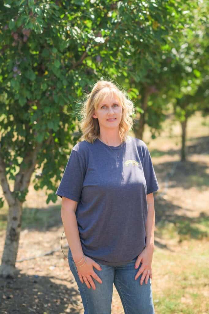 woman stands in prune orchard