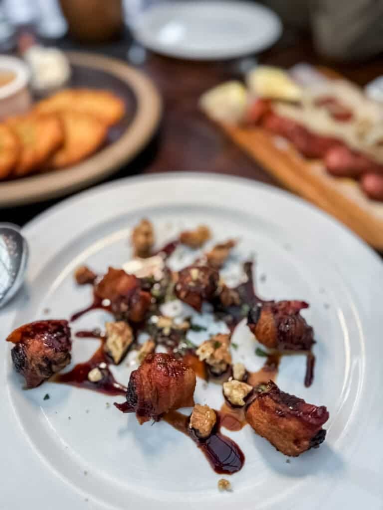 bacon wrapped prunes on a white plate