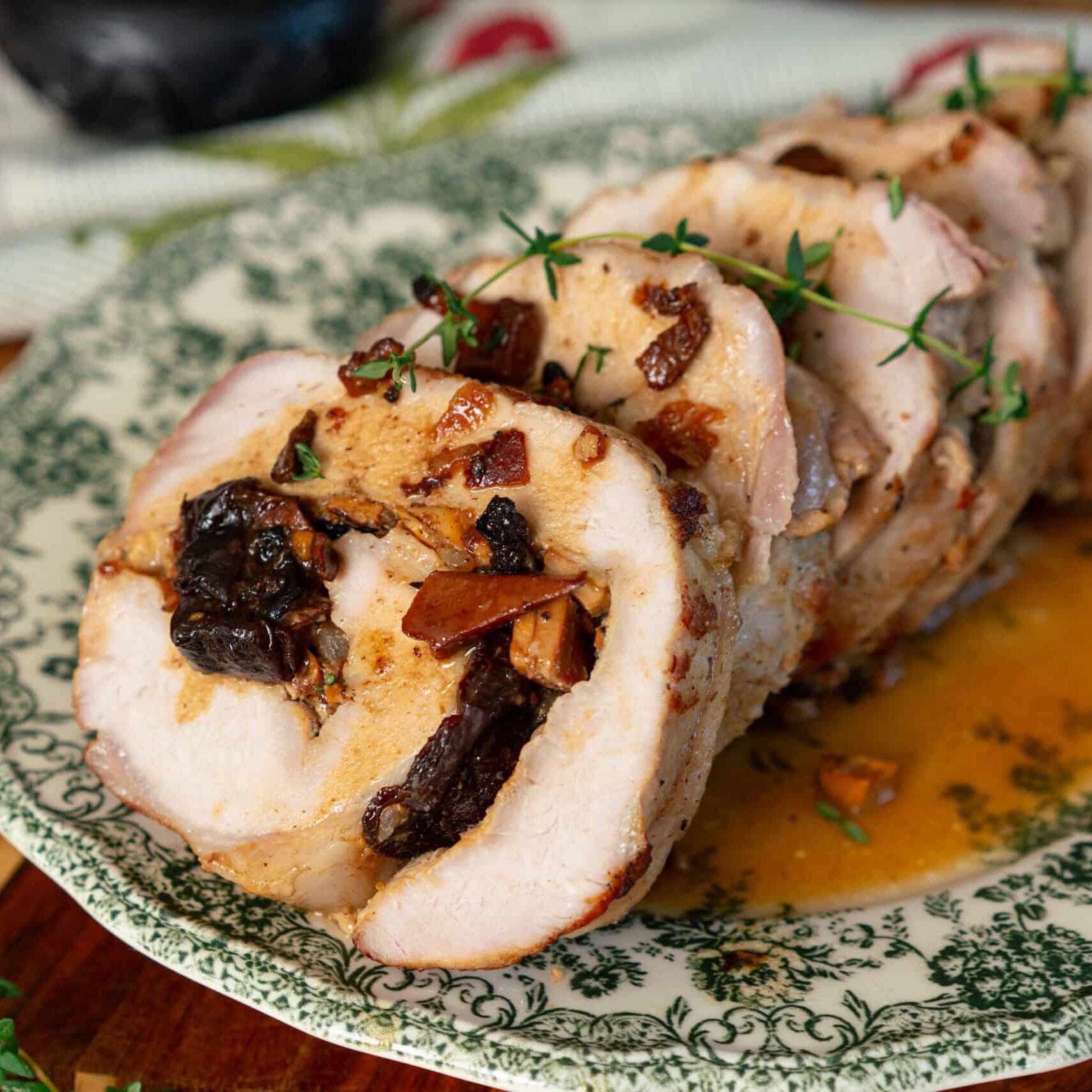 sliced pork roulade on a green and white plate