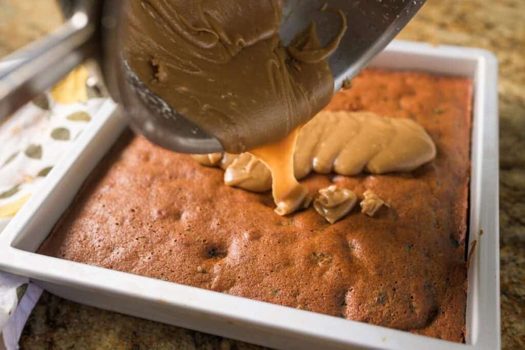 pouring butterscotch frosting on spice cake