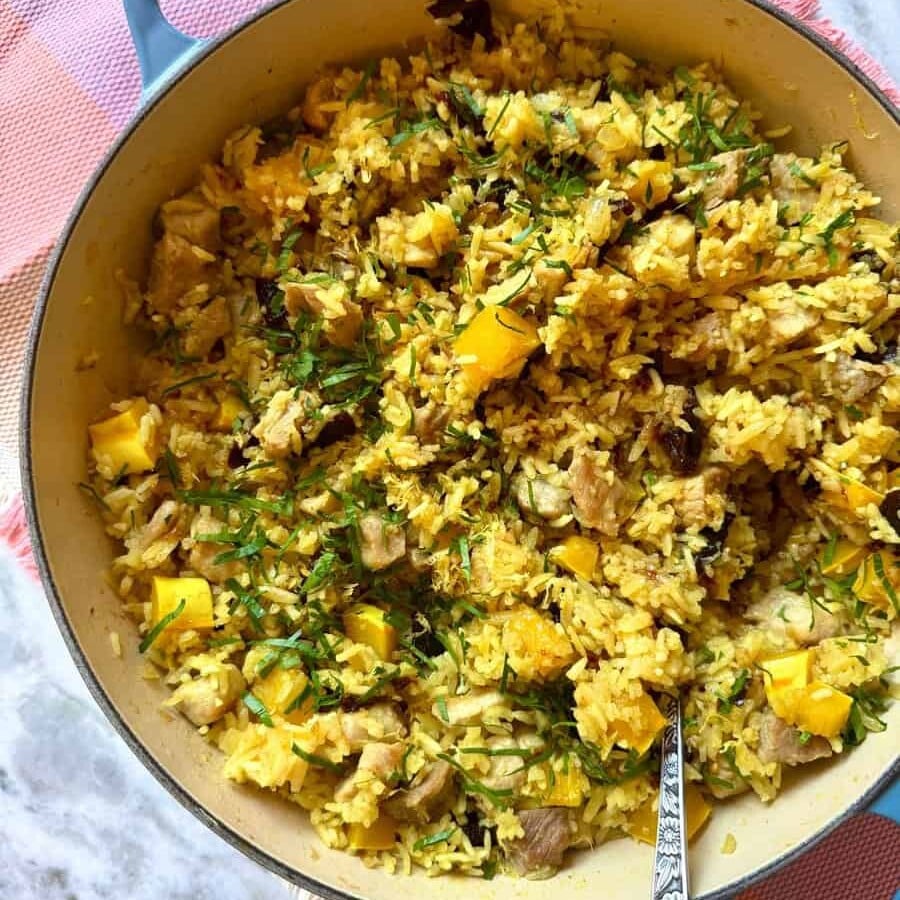 pork and orzo pilaf in a blue cast iron pan