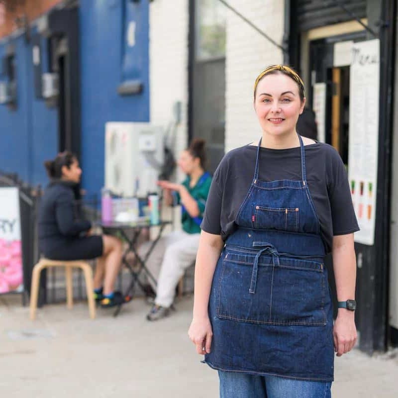 woman standing on sidewalk outside bakery in Brooklyn